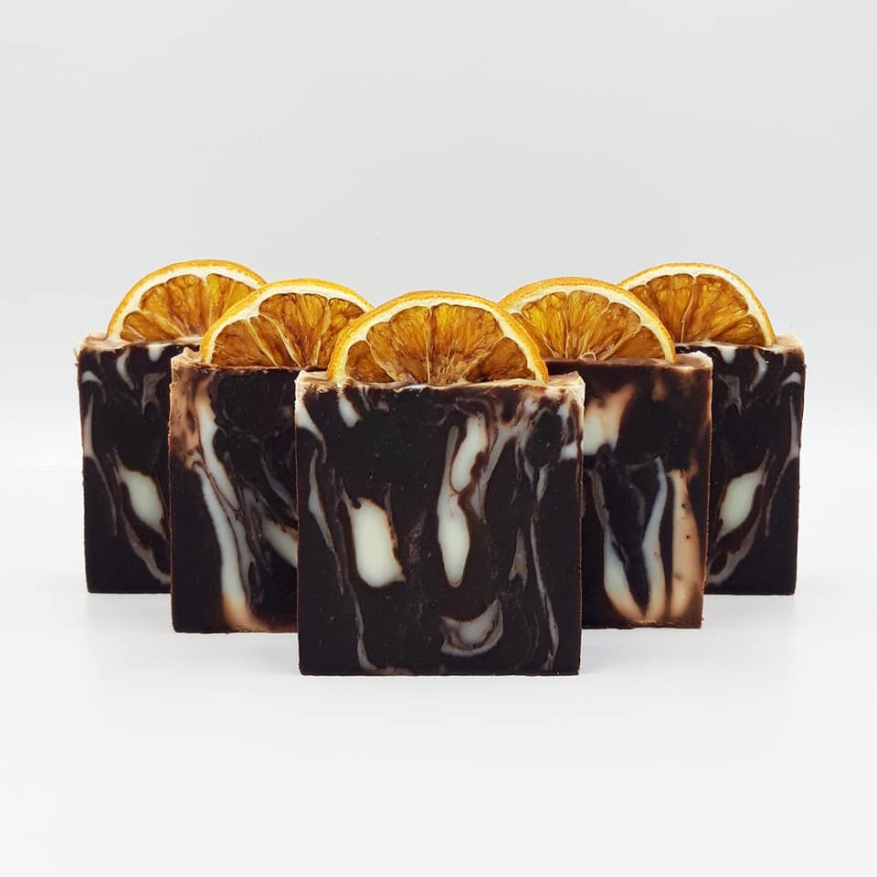 A set of bars of soap with a marbled black and white appearance, adorned with slices of dried orange.