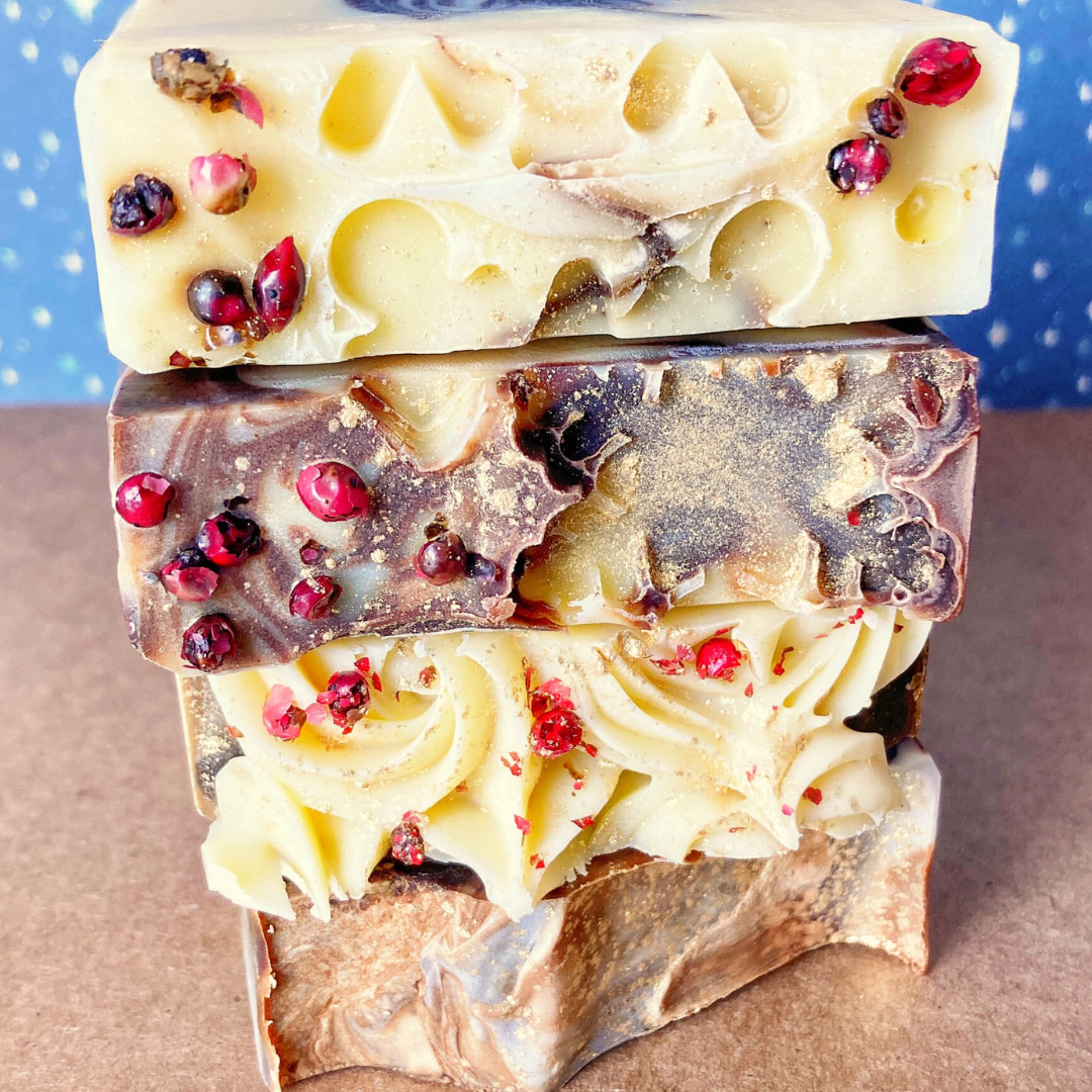 Stack of handmade soaps with visible spices and decorative elements integrated into the soap texture.