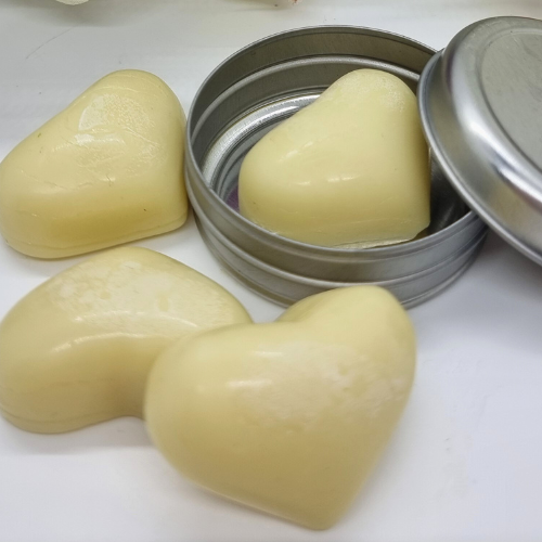 Cream coloured heart shaped lotion bars with a silver open tin