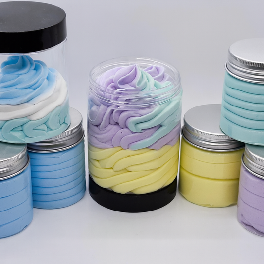 Jars filled with colourful, swirled mousse whipped soap on a white background