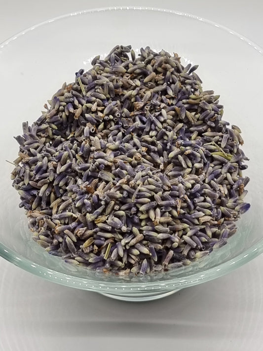 glass bowl containing dried lavender flowers, their colour ranges from deep purple through to a green shade at the base of each flower.