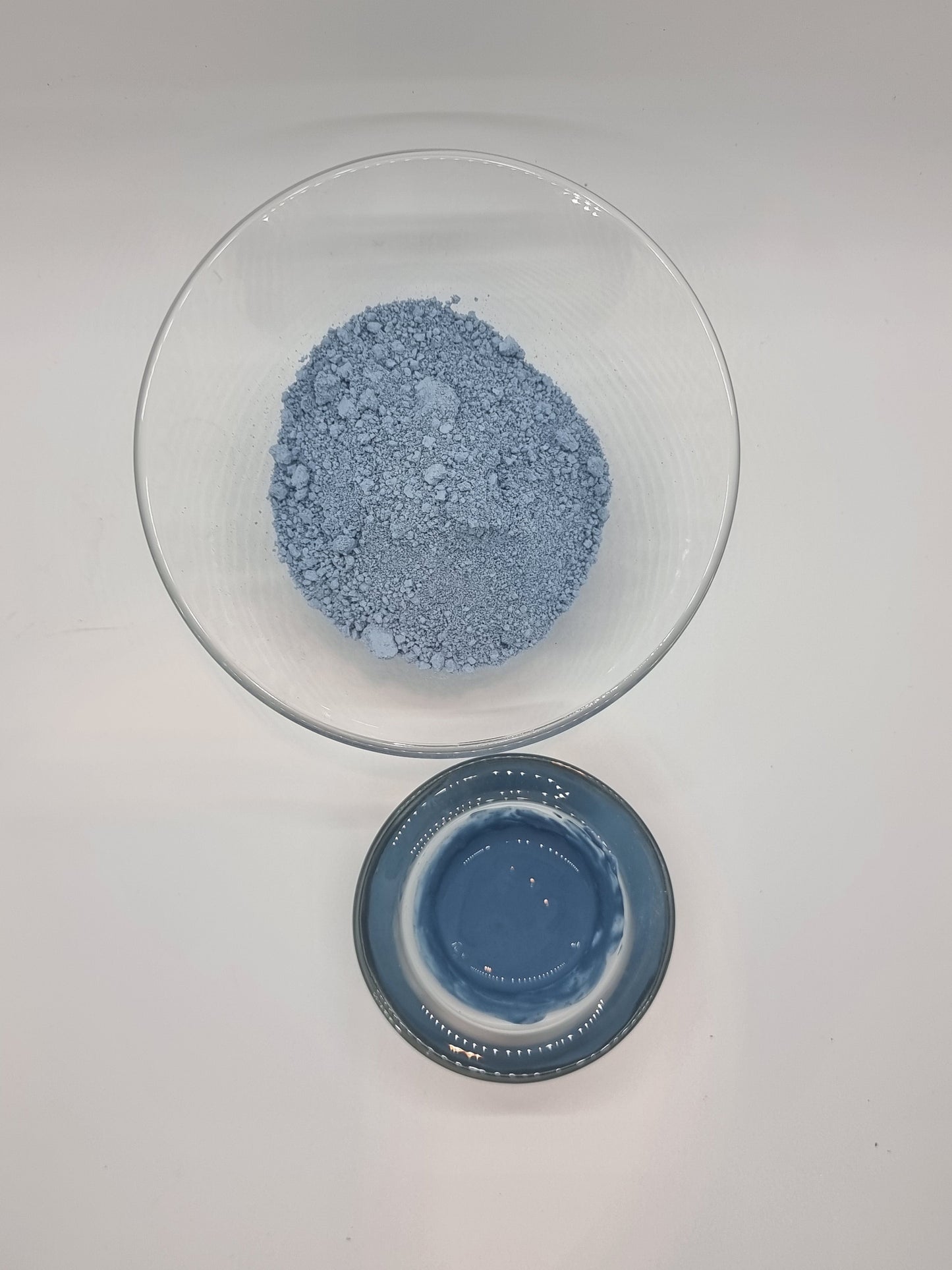 Serbian Blue clay in powder form and mixed with water showing the bright blue colour of the clay 